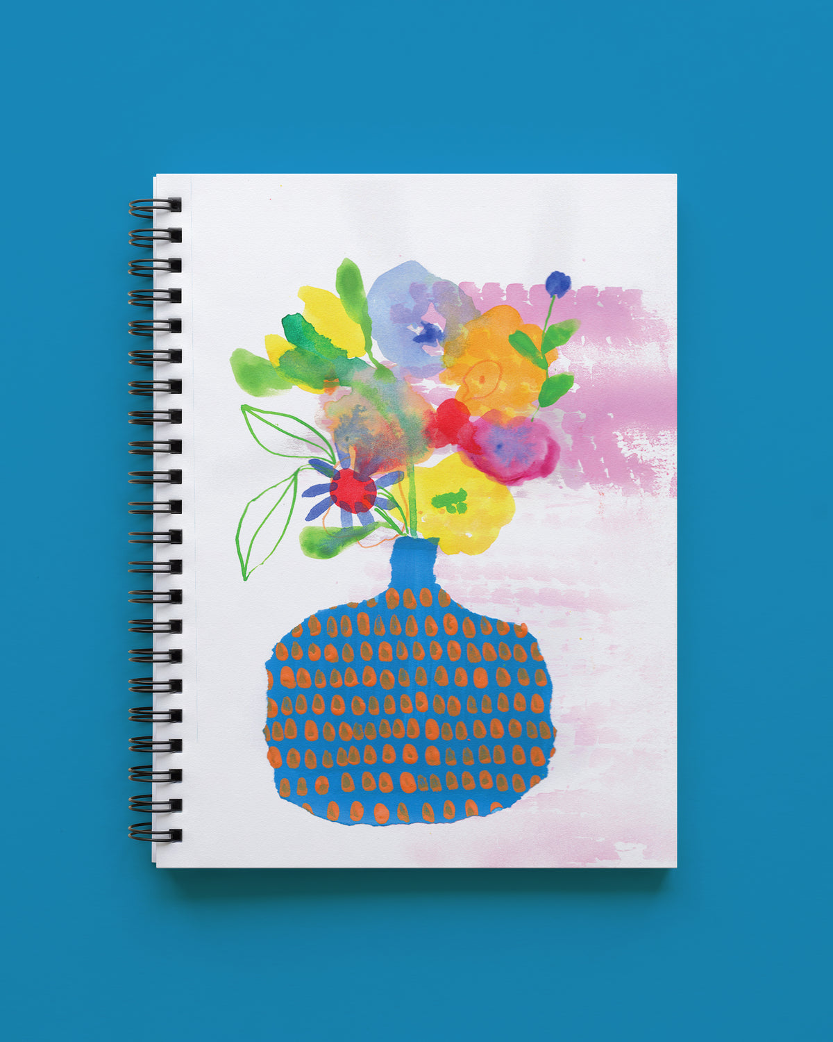Wire bound notebook with a white cover showing a bouquet of yellow, orange, pink, and lavender watercolor flowers in a round blue vase with orange dots, shown on a bright blue background