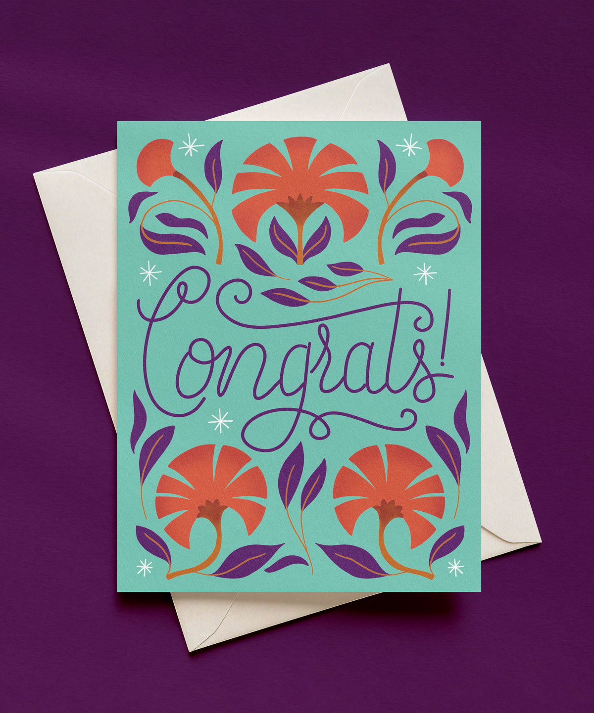 Mint green Congrats greeting card with purple script lettering, surrounded by coral flowers, purple leaves, and white sparkles, shown with a cream envelope